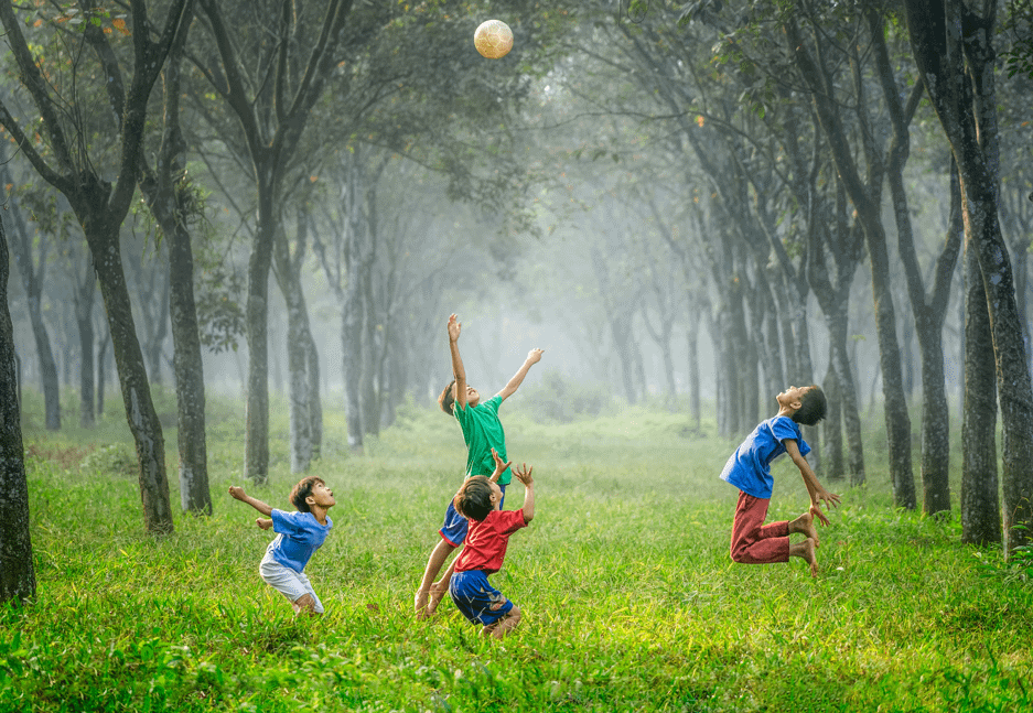 Kids jumping in the air in a lush, green forest