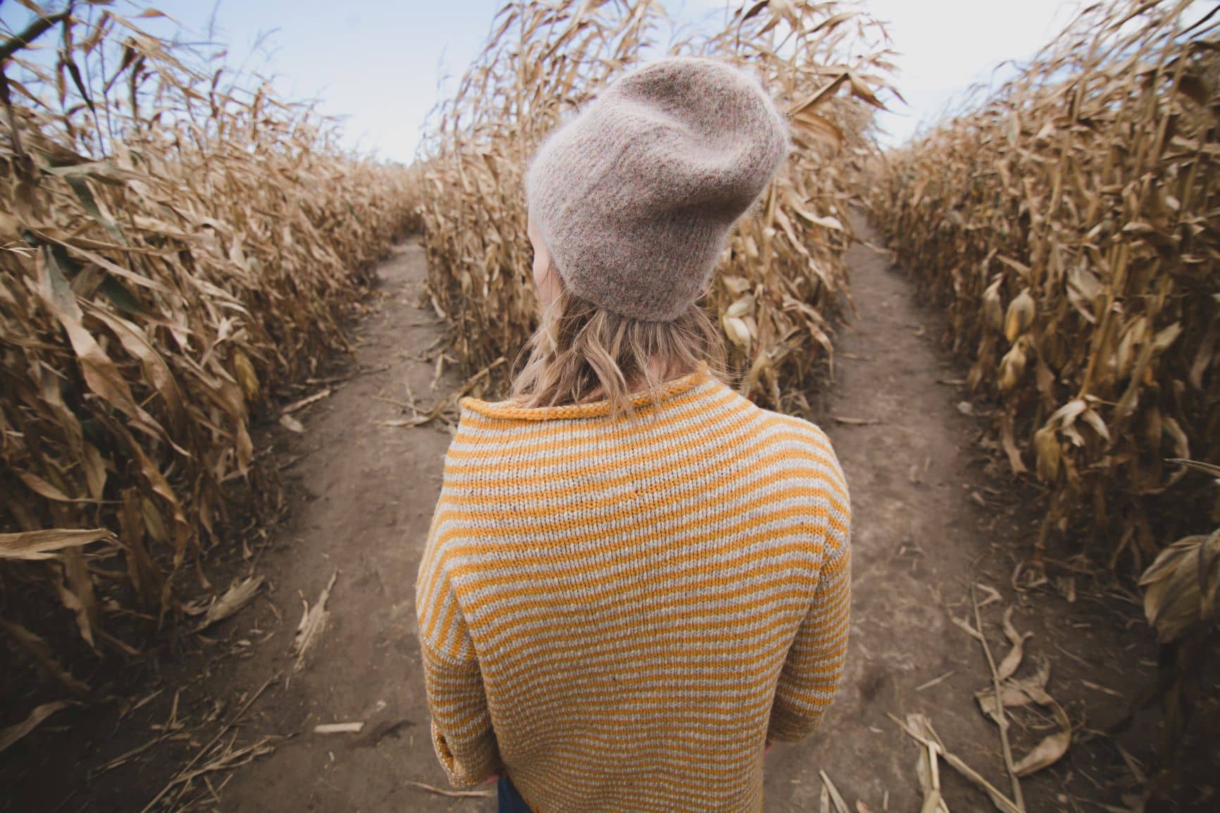 Woman standing between two roads in field of wheat
